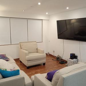 sala de estar con 2 sofás y TV de pantalla plana en DEPARTAMENTO RECAVARREN (SURQUILLO/MIRAFLORES), en Lima