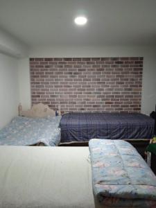 a bedroom with two beds and a brick wall at DEPARTAMENTO RECAVARREN (SURQUILLO/MIRAFLORES) in Lima