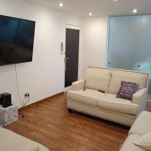 sala de estar con sofá y TV de pantalla plana en DEPARTAMENTO RECAVARREN (SURQUILLO/MIRAFLORES), en Lima