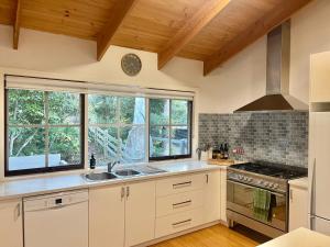 a kitchen with a sink and a stove and windows at Two Mountains Lodge - Modern Alpine Retreat with Spa - 3mins to Mt Buller in Mount Buller
