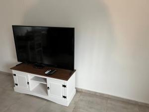 telewizor z płaskim ekranem siedzący na białej szafce w obiekcie Apart del Este 2 w mieście Paysandú