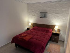 パイサンドゥーにあるApart del Este 2のベッドルーム1室(赤いベッド1台、ナイトスタンド2台付)