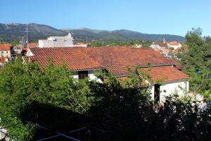 a house with red tile roofs with mountains in the background at Apartments and rooms by the sea Vrboska (Hvar) - 540 in Vrboska