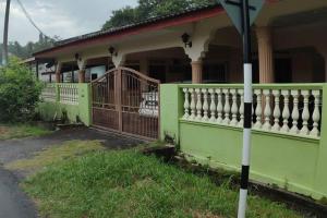 a green house with a porch with a fence at Mai KKB Homestay in Kuala Kubu Bharu Taman Juta in Kuala Kubu Bharu