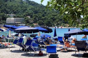 un groupe de personnes assises dans des chaises et des parasols sur une plage dans l'établissement Apartments and rooms with parking space Dubrovnik - 11207, à Dubrovnik