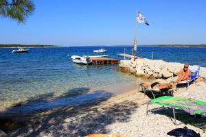 2 personnes assises sur des chaises longues sur une plage dans l'établissement Apartments with a parking space Stinjan, Pula - 11648, à Štinjan