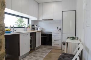 eine Küche mit weißen Schränken und einem schwarzen Kühlschrank in der Unterkunft Sabor@Arte in Couto de Esteves