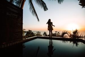 a woman standing on the edge of a swimming pool at Casas del Sol - Luxury Boutique Villas in Koh Tao