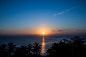 a sunset over the ocean with palm trees in the foreground at Casas del Sol - Luxury Boutique Villas in Koh Tao