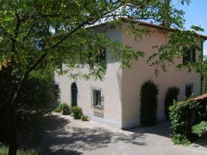 Una casa blanca con un árbol delante. en Belvilla by OYO Casa Prati, en Ghizzano