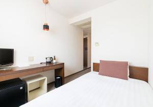 a bedroom with a bed and a desk with a tv at Hotel day by day in Hamamatsu