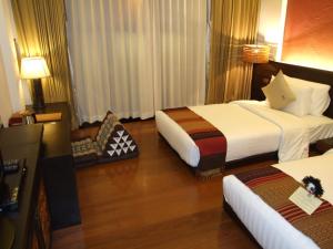 a hotel room with two beds and a television at De Lanna Hotel in Chiang Mai