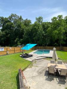 a pool with a table and chairs and an umbrella at The Cozy Hidden Gem in Charleston