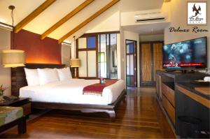 a bedroom with a bed and a flat screen tv at De Lanna Hotel in Chiang Mai