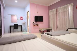 1 dormitorio con 2 camas y TV en la pared en OYO Homes 90575 CK Bahau Homestay en Bahau