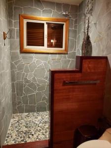 ein Badezimmer mit einer Holztür und einer Steinmauer in der Unterkunft Cabina Harlequin at Margarita Hills Farm in Cocles