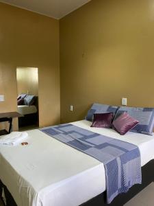 ein Schlafzimmer mit einem großen Bett mit lila Kissen in der Unterkunft HOTEL LISBOA in Capanema