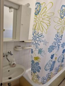 a bathroom with a shower curtain with flowers on it at Apartments Smilja - great location in Supetar