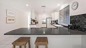 a kitchen with a counter and two wooden stools at My Shell Boat Harbour 55 Blanch Steet in Boat Harbour