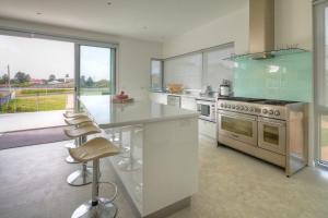 a kitchen with a stove and a counter with stools at Villa Moyne in Port Fairy
