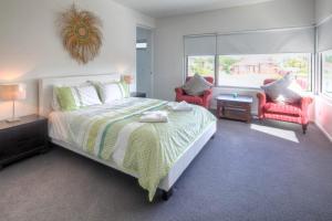 a bedroom with a large bed and two red chairs at Villa Moyne in Port Fairy