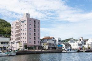 a tall white building next to a river with boats at Iki Marina Hotel in Iki