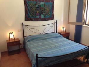 a bed in a room with two tables and a painting on the wall at Kalypso in Sciacca