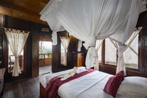 Schlafzimmer mit einem Bett mit weißer Bettwäsche und Vorhängen in der Unterkunft Mushroom Beach Bungalows in Nusa Lembongan