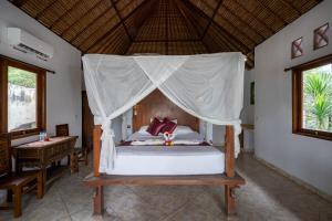 1 dormitorio con 1 cama con dosel en Mushroom Beach Bungalows, en Nusa Lembongan