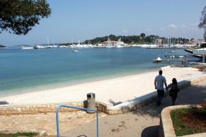 a man and a woman walking on the beach at Apartments and rooms with WiFi Vrsar, Porec - 3007 in Vrsar