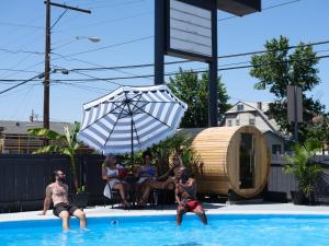 a group of people in a swimming pool with an umbrella at Motolodge in Pendleton