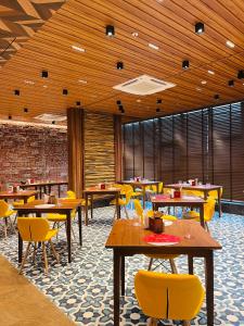 a restaurant with wooden ceilings and tables and yellow chairs at Ginger Mumbai, Goregaon in Mumbai