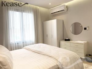 um quarto branco com uma cama, uma cómoda e um espelho em Kease Malqa A-6 Royal Touch XZ56 em Riyadh