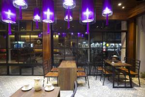 Nakorn De Sukhothai Hip Hotel في سوخوثاي: مطعم بطاولات وكراسي وانوار ارجوانية