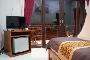 a hotel room with a television and a bed at Puri Bisma Ubud - 4 Bedroom PRIVATE VILLA - 10 min walking to Ubud Center in Ubud