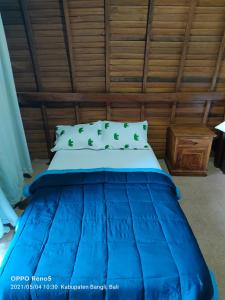 a blue bed in a room with a wooden ceiling at Batur Water Park Villa in Bangli