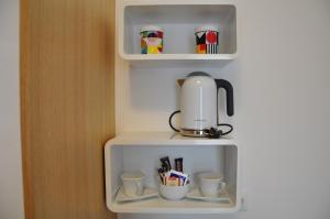 a coffee maker and cups on a shelf at Rooms Indigo Bundek in Zagreb