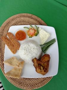 a plate of food with rice and meat and vegetables at Batur Water Park Villa in Bangli