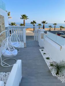 einen Gehweg mit weißen Bänken und dem Strand in der Unterkunft Suitenes Coast in Rethymno