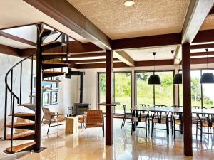 une salle à manger avec un escalier en colimaçon, une table et des chaises dans l'établissement UMIBE IseShima, à Shima