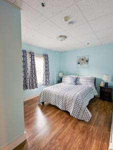a bed in a bedroom with blue walls and wooden floors at Downtown Apartments in Bar Harbor in Bar Harbor