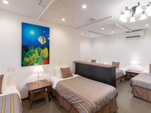 a room with three beds and a painting on the wall at Hotel Koza in Okinawa City