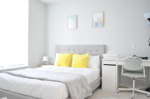 - une chambre blanche dotée d'un lit avec des oreillers jaunes et d'un bureau dans l'établissement 2102-6638 Dunblane Burnaby, à Burnaby