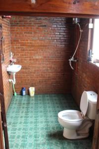 y baño con aseo y lavamanos en una pared de ladrillo. en Teak house en Timuran