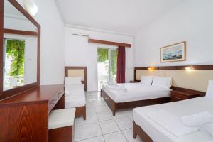 a hotel room with two beds and a desk at Chrissafis Hotel in Panagia