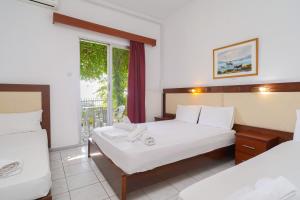a hotel room with two beds and a window at Chrissafis Hotel in Panagia