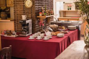 una mesa roja con tazas y platos de comida. en Acacia Guesthouse Klerksdorp en Klerksdorp