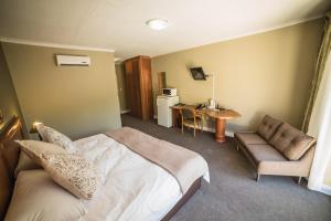 a bedroom with a bed and a chair and a desk at Acacia Guesthouse Klerksdorp in Klerksdorp