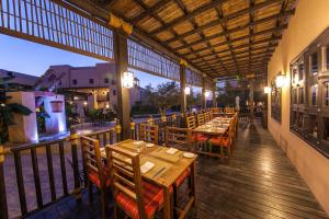 un restaurante con mesas de madera y sillas en una terraza en Atana Musandam Resort, en Khasab