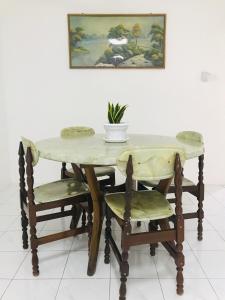 einem Holztisch mit zwei Stühlen und einer Pflanze darauf in der Unterkunft Alyn Home Batu Pahat II Wifi Coway in Kampong Mohamad Noor